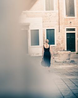 Rear view of woman standing against building