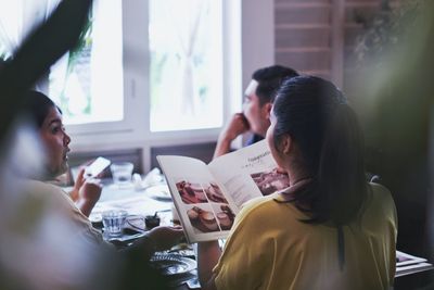 Man and woman using smart phone while sitting on table