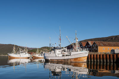 Boats in sea against clear blue sky