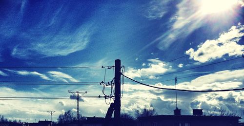 Low angle view of electricity pylon against cloudy sky