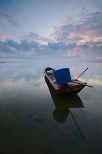 Boat floating on water against sky during sunset