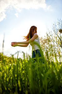 Rear view of woman standing on field against sky