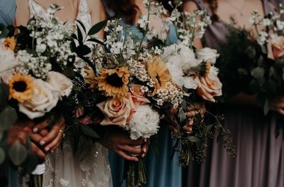 Midsection of bridesmaids holding bouquet