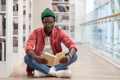 Focused african american guy preparing materials for upcoming lecture reading book in university