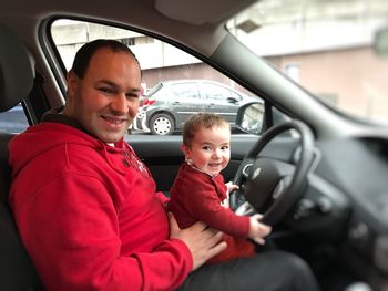 Portrait of happy father with son on driving seat