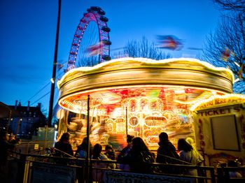 People at amusement park against sky at night