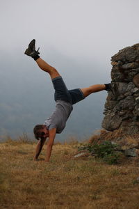 Full length of woman doing handstand on field against sky