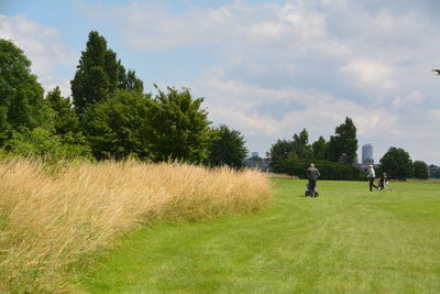 People on golf course against sky