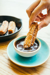 Cropped hand dipping food in chocolate sauce