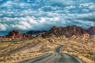 Empty road amidst landscape against sky