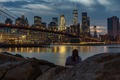 Rear view of woman with illuminated bridge in background