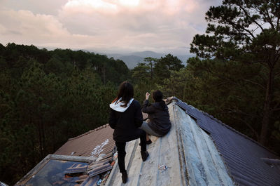 Friends on roof against sky during sunset