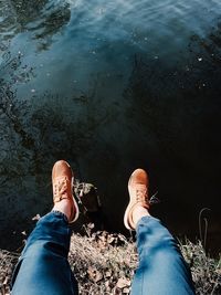 Low section of woman sitting on cliff over lake