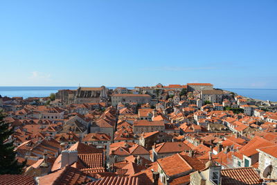 High angle view of houses by sea against clear blue sky