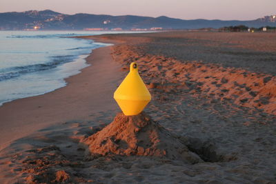 Yellow umbrella on beach against sky during sunset