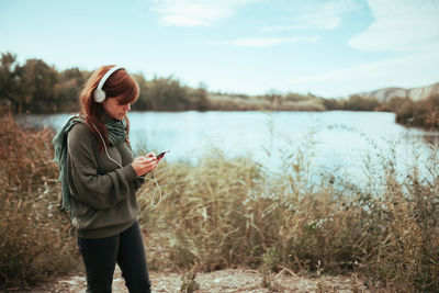 Young woman looking at camera while standing on lake