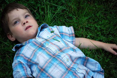 High angle view of boy lying on grassy field