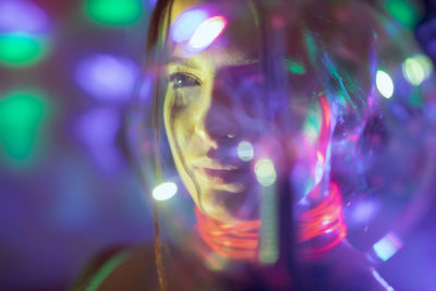 Close-up of colorful lights falling on woman face