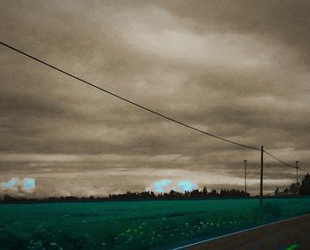 Electricity pylon on field against cloudy sky