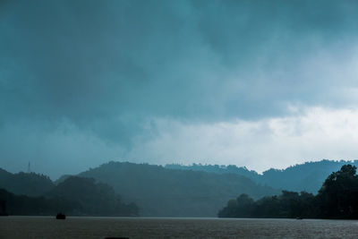 Scenic view of lake by mountains against sky