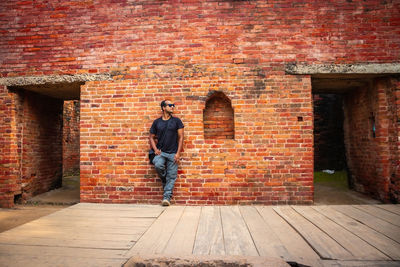 Man standing against brick wall