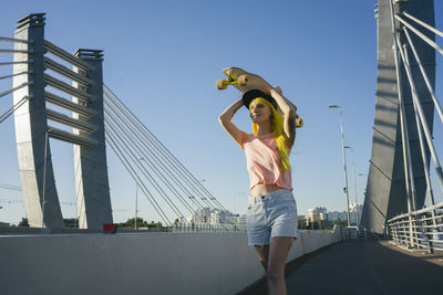 Woman standing on bridge against clear sky in city