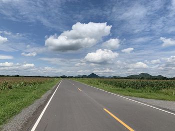 Road amidst field against sky