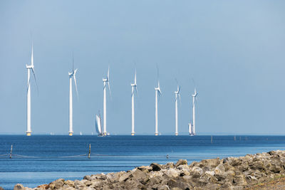 Scenic view of sea against clear sky, windmills by sea against sky, windmills park westermeerdijk