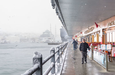 People walking on bridge in city during winter