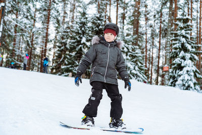 Full length of boy snowboarding on snow covered land