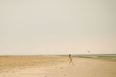 Man walking on beach against clear sky