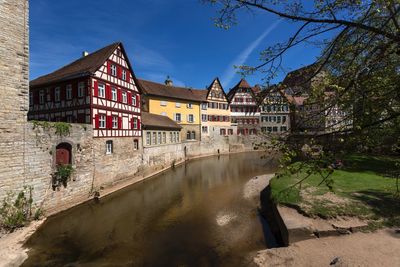 Buildings by canal against sky in city