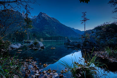 Scenic view of lake and mountains against clear blue sky