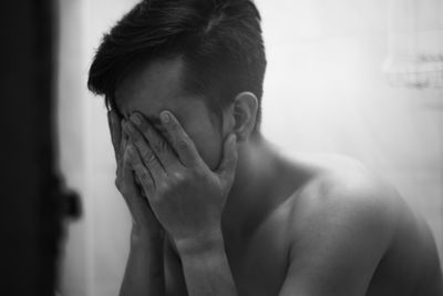 Close-up of stressed man covering face with hands