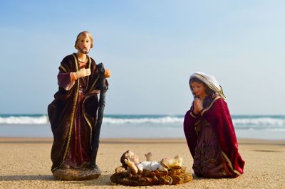 Friends sitting on shore at beach against clear sky