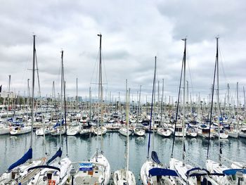 Boats moored in calm sea against cloudy sky