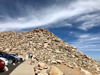 People on rock formation against sky