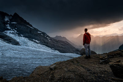 Rear view of man standing on rock against sky