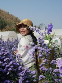 Portrait of smiling woman with purple flowers against plants