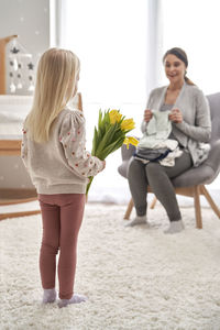 Rear view of daughter holding tulip bouquet while looking at mother