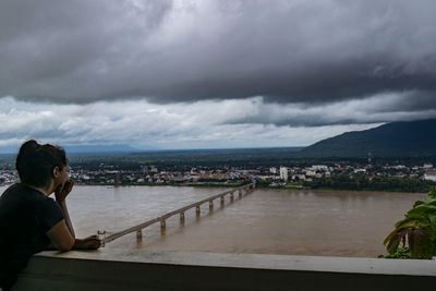 Woman looking at river against cloudy sky