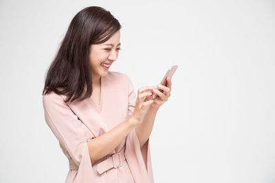 Young woman using smart phone against white background