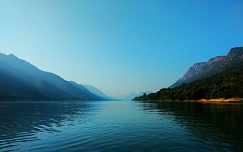 Scenic view of lake and mountains against clear blue sky