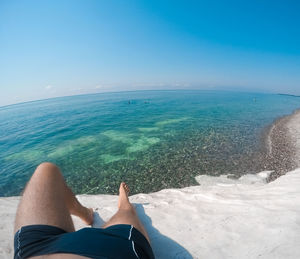 Low section of person in sea against sky