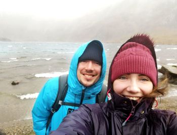 Portrait of smiling couple at beach during winter