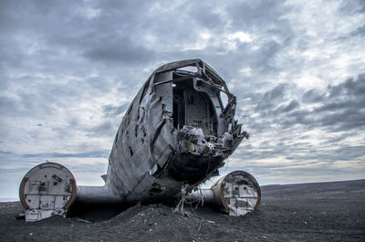 Abandoned airplane on land against sky