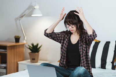 Young woman using phone while sitting on table