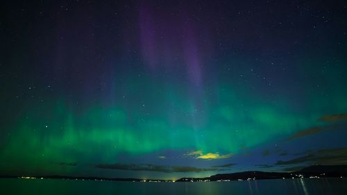 Low angle view of aurora borealis over lake