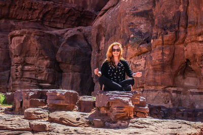 Woman looking away while sitting on rock