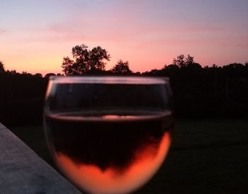 Close-up of beer in glass on table against sunset